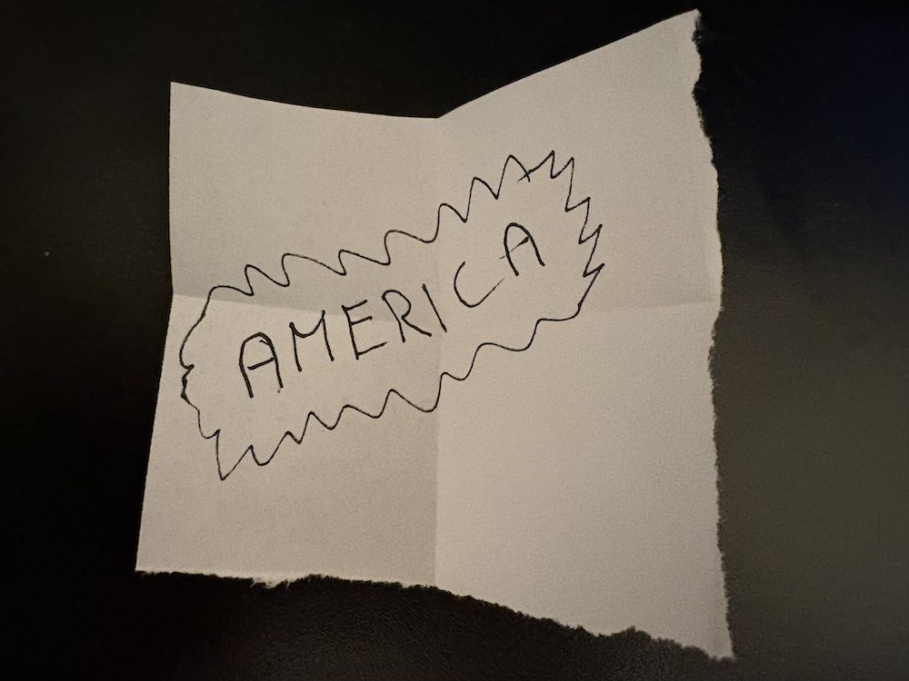Rozložený papírek s ručně napsaným slovem AMERICA.